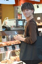 注文した惣菜を笑顔で待つマサヒロ。