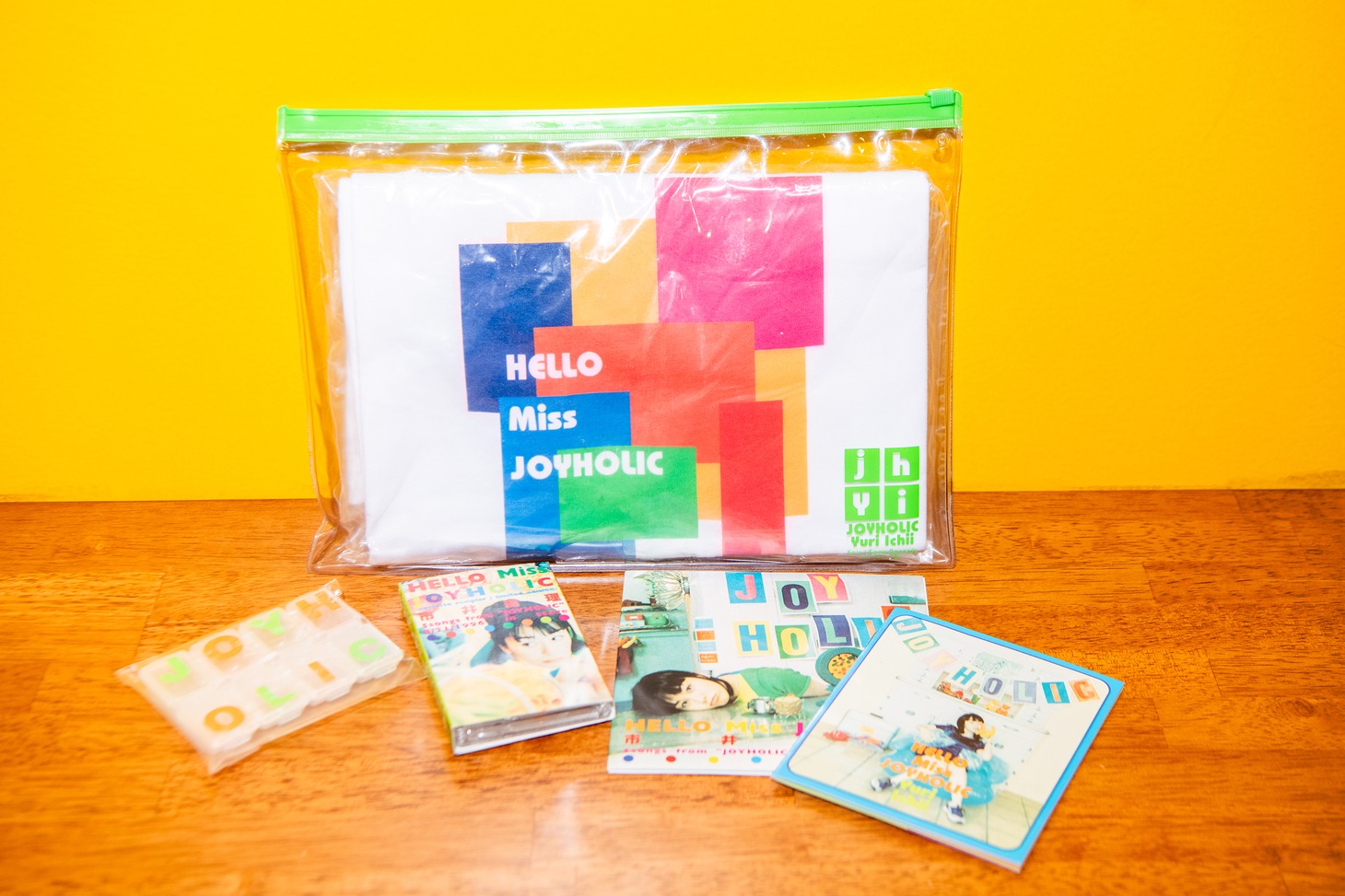 「JOYHOLIC」のプロモーションキット一式。Tシャツ、ピルケース、カセット、CD、ミニブック。