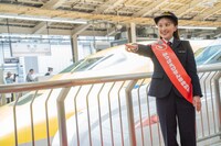 Zポーズで出発進行の合図を行う百田夏菜子。奥にはドクターイエロー。