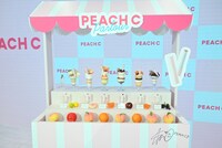 「ジューシーネクターリップスティック」が展示されたワゴン。ワゴンにはマシロ（Kep1er）のサイン入り。