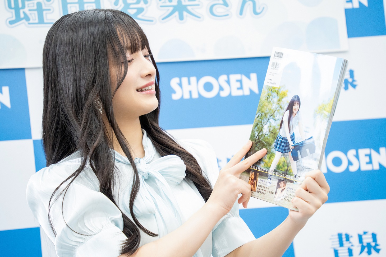 制服姿のカットが使われた写真集の裏表紙を見る蛭田愛梨（虹のコンキスタドール）。