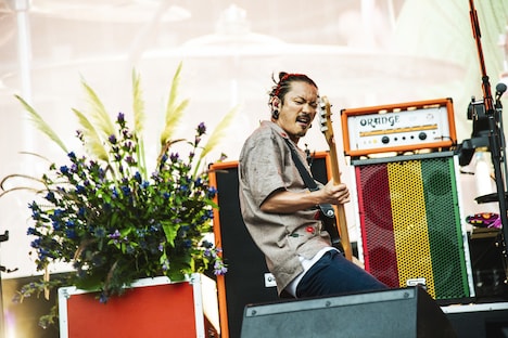 熊本の県花・りんどうをバックに演奏するKENTA（Vo, B / WANIMA）（Photo by Yukihide "JON..." Takimoto）