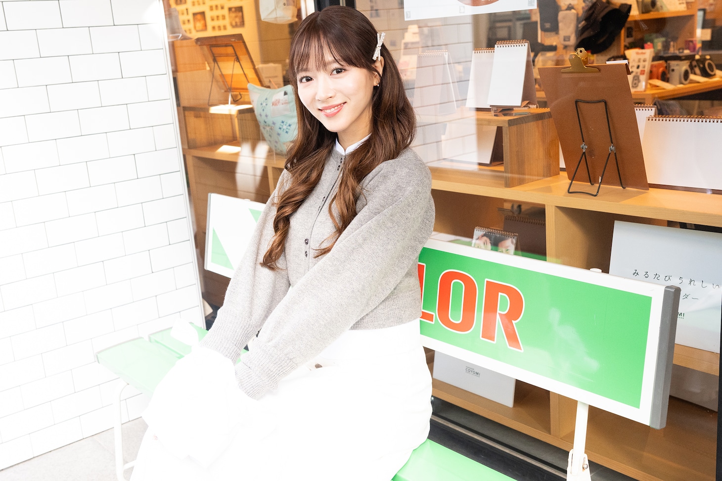 レトロなフジカラーのベンチに腰掛ける中山莉子。
