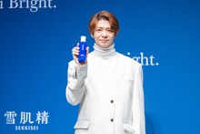 雪肌精のボトルを手にほほえむ岸優太。