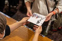 ファンに特典を手渡しする伊藤賢治。