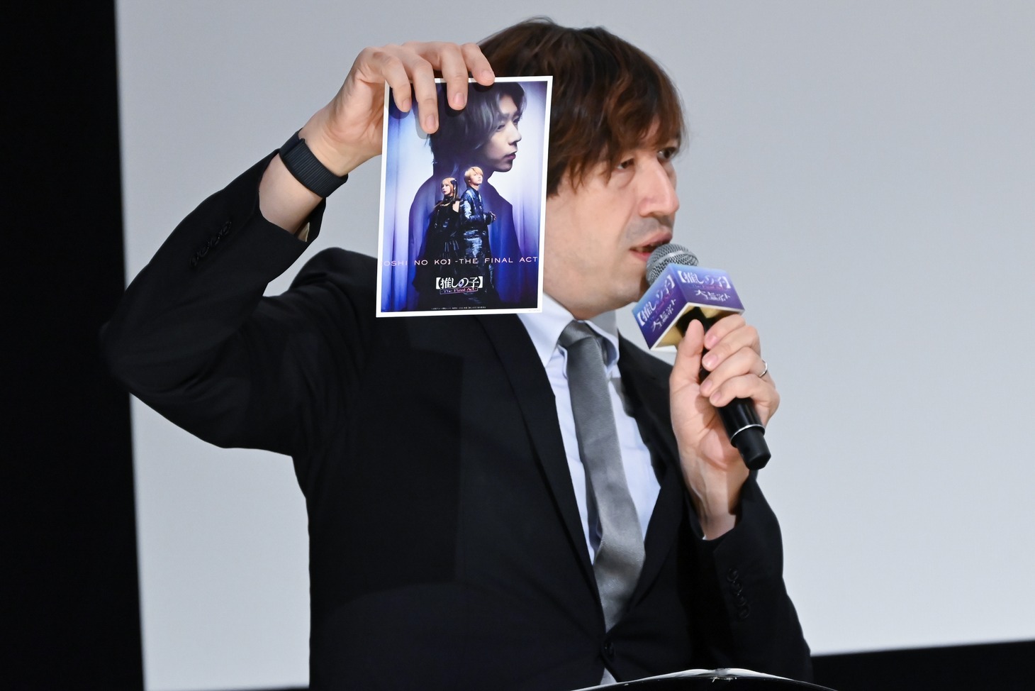 入場者プレゼント第2弾を持つ司会のサッシャ。