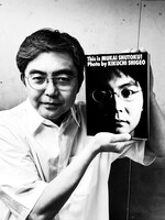 フォトアルバム「This is MUKAI SHUTOKU! Photo by KIKUCHI SHIGEO」を手にする向井秀徳。