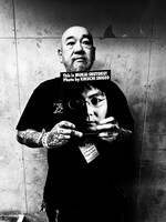 フォトアルバム「This is MUKAI SHUTOKU! Photo by KIKUCHI SHIGEO」を手にする菊池茂夫。