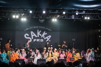 おもむろにステージ上で電話をかけるヤマモトショウ（後列右端）。