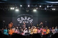 ステージ上で電話をかけ次回の出演交渉をするヤマモトショウ（後列右端）と電話を受ける宮野弦士（後列左端）。