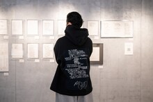 自らの原書と対峙するKREVA。着用しているのはリリックがあしらわれた、ALMOSTBLACKとのコラボパーカー。