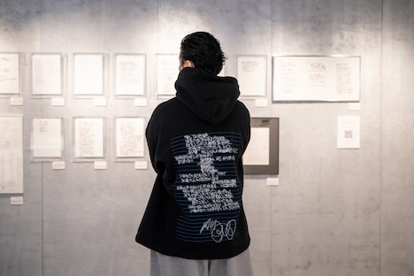 自らの原書と対峙するKREVA。着用しているのはリリックがあしらわれた、ALMOSTBLACKとのコラボパーカー。