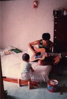 1歳頃。ギターを弾く父と、自宅にて。