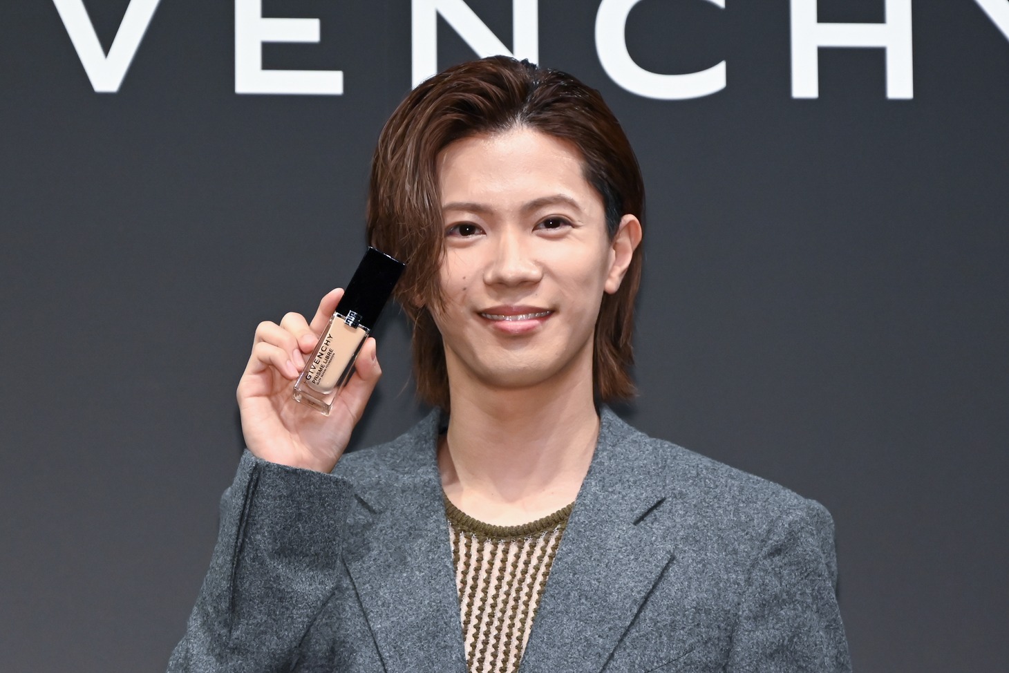 「ジバンシィ・リーブル・グロウ・セラム・ファンデーション」を手にほほえむ神宮寺勇太。