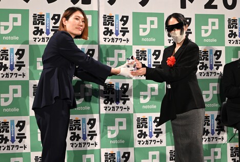 坂本編集長からトロフィーを受け取るつるこ。(右)。