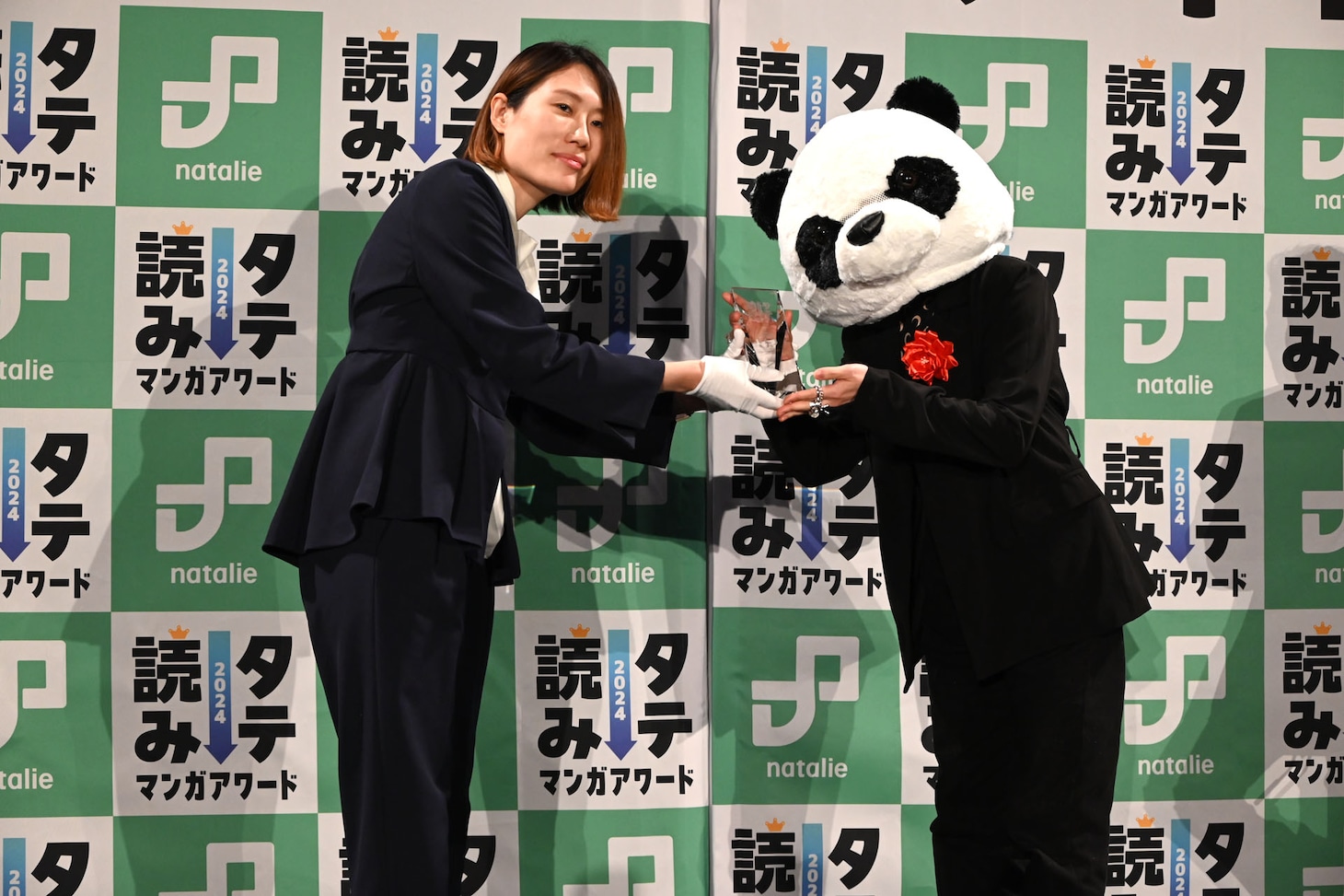 坂本編集長からトロフィーを受け取る阿賀沢紅茶（右）。