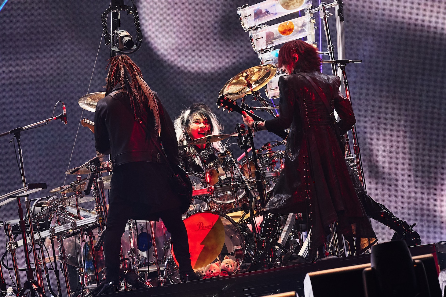 向かい合って演奏するINORAN（G）、真矢（Dr）、SUGIZO（G, Violin）。