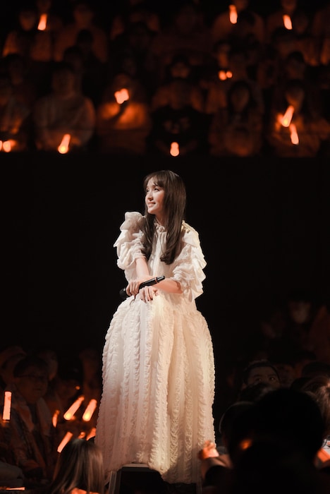 1階席の中央で脚立に腰掛けて歌う百田夏菜子。(撮影:上飯坂一)