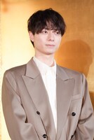 金屏風の前に立つ作間龍斗。