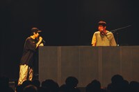 DJブースに肘を置きながら「これがあるとテレビ番組みたいで饒舌になる」と語るcp（左）。（撮影：横山マサト）