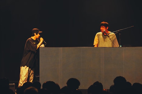 DJブースに肘を置きながら「これがあるとテレビ番組みたいで饒舌になる」と語るcp（左）。（撮影：横山マサト）