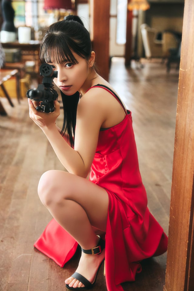 真っ赤なドレスでライフルを構える汐見まとい。（撮影：高橋慶佑 / ヘアメイク：海瀬志津奈［JULLY］ / スタイリング：大橋みずな）