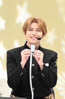 「推し生存」御守を手にするタカシ。