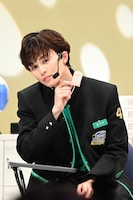 すまし顔で「推し笑顔」御守を持つタクヤ。