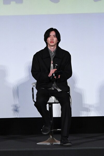 右手にマイク、左手にスマートフォンを持つ道枝駿佑。