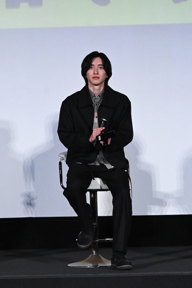 右手にマイク、左手にスマートフォンを持つ道枝駿佑。