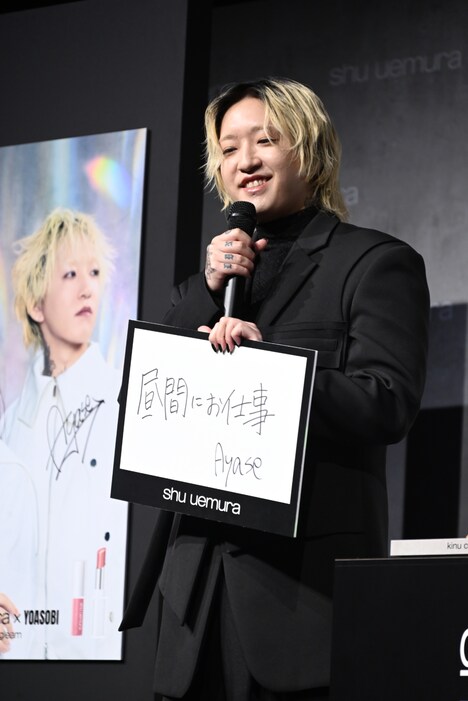 「昼間にお仕事」のフリップを出すAyase。