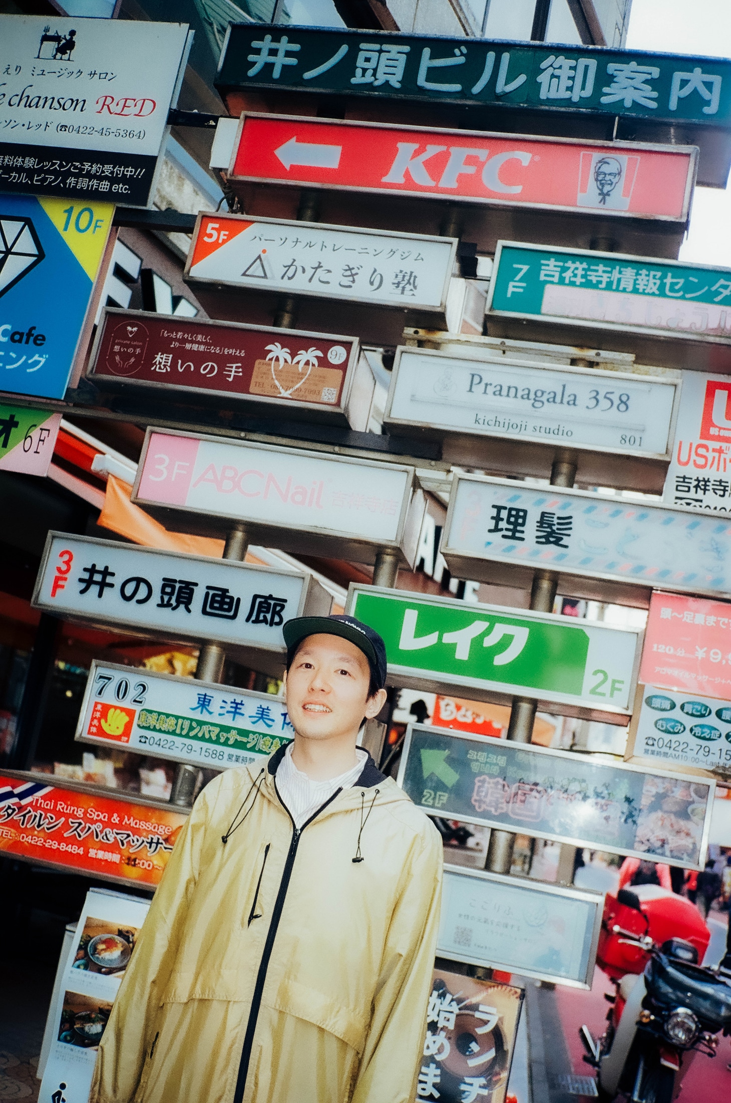 駅前にある井の頭ビルの看板と高城晶平。高城は最近、ビル内のお店でNintendo Switchのリモコンを修理してもらったという。