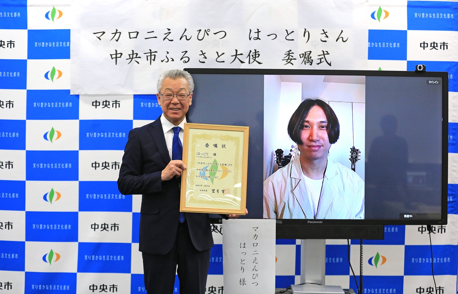 左から山梨県中央市長の望月智氏、モニタ越しにほほえむはっとり。