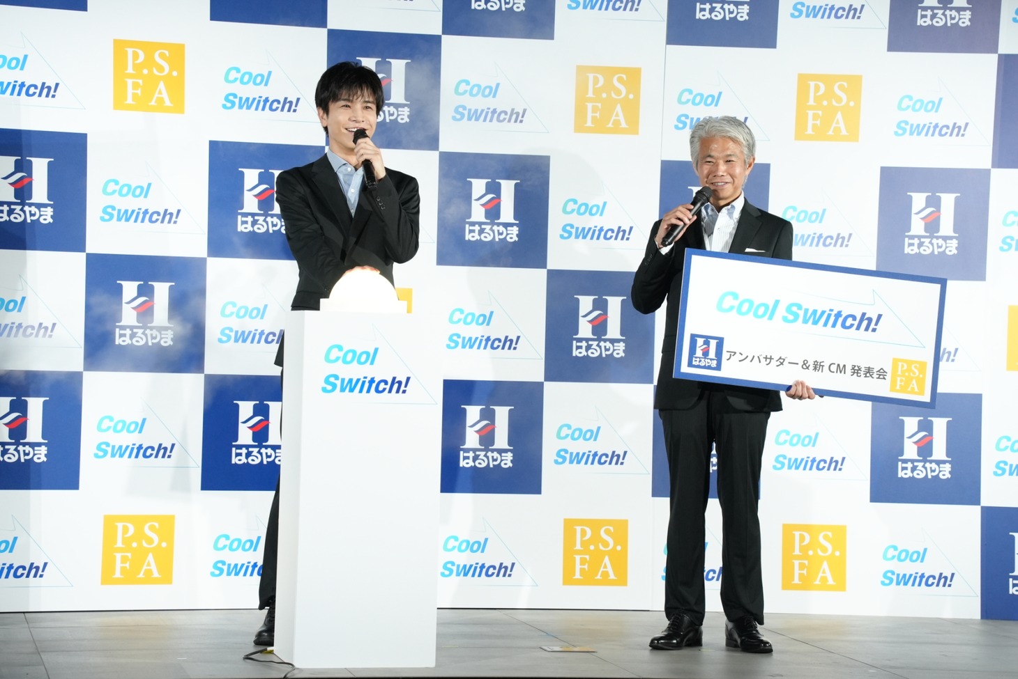 スイッチを押した岩田剛典とスイッチを押す岩田剛典と、はるやま商事の治山正史会長。