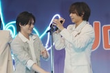 中村海人(右)にマイクスタンドを差し出す松田元太(左)。