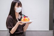 開演前の楽屋口、安本彩花にサプライズでバースデーケーキを渡そうと壁際に隠れるえびちゅう仲村悠菜。