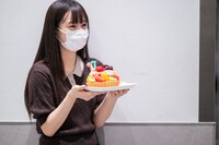 開演前の楽屋口、安本彩花にサプライズでバースデーケーキを渡そうと壁際に隠れるえびちゅう仲村悠菜。