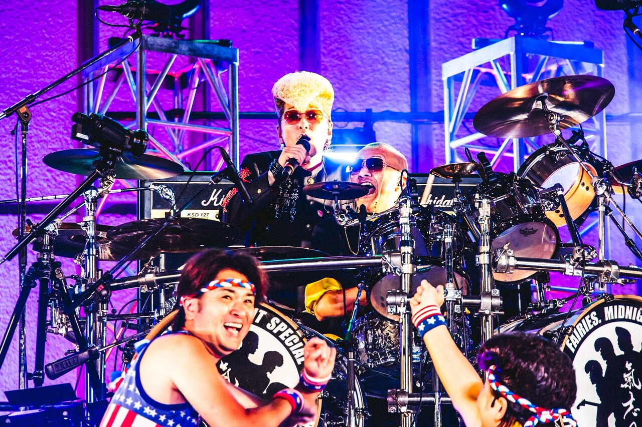 ドラムセットに向かう白鳥雪之丞と、その後ろで歌う綾小路翔。（撮影