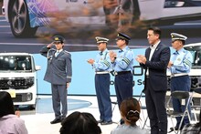 拍手で迎えられ、敬礼するリョウガ交通安全大使。