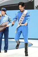 自転車にまたがる動きでクイズの答えを考えるリョウガ交通安全大使。