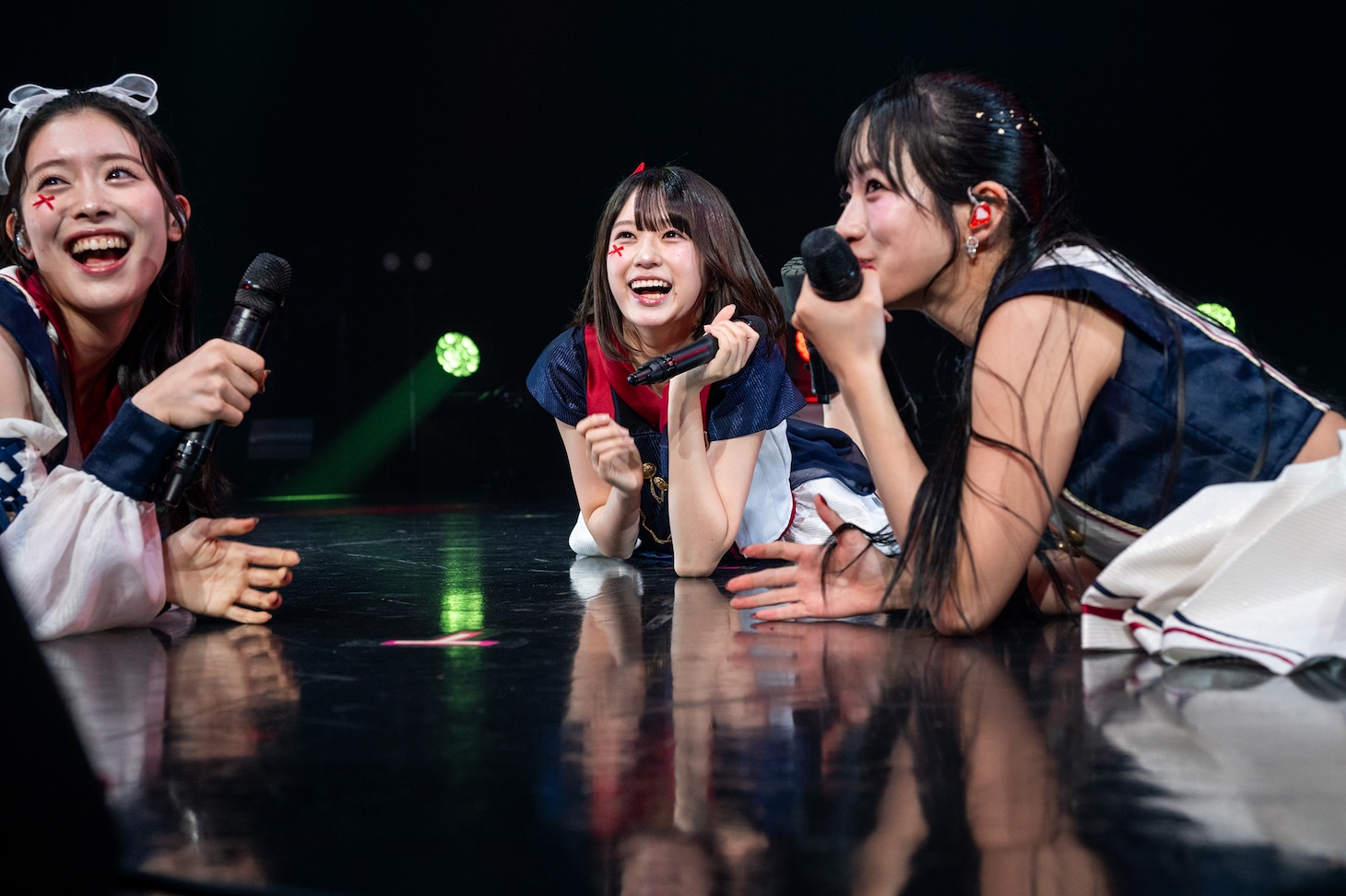 ステージに寝そべる風見和香、小久保柚乃、桜木心菜（左から）。