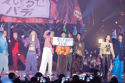 「愛してるぜバディ」と書いたタオルを掲げるBUDDiiS。