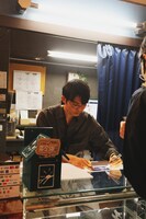 ポストカードにサインを入れる折坂。