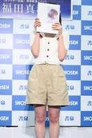 記者からの無茶振りに笑い、写真集で顔を隠す福田真琳（つばきファクトリー）。