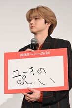 真顔で「ユーキの呪い」のフリップを持つユーキ。