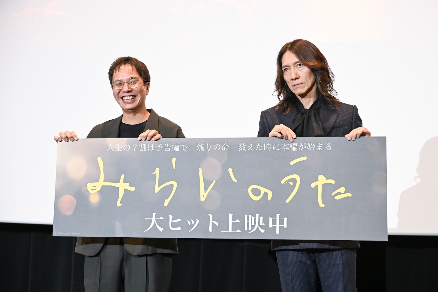 パネルが斜めになっていることを指摘されてカメラマンを睨みつける吉井和哉（右）。