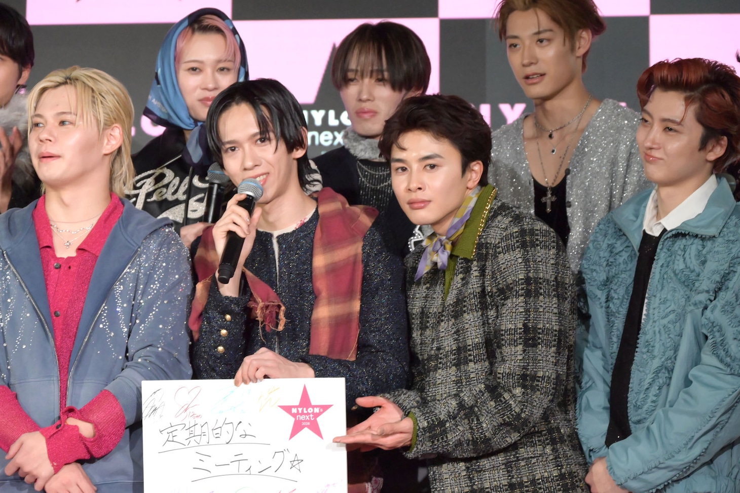 真顔でリョウガのフリップを紹介するタクヤ（下段中央右 / 超特急）。