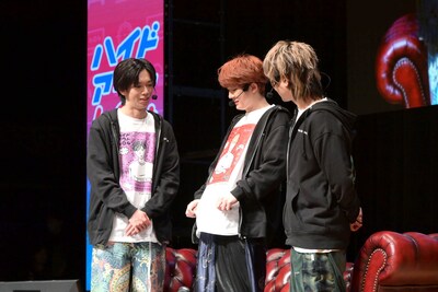 グッズTシャツにプリントされた似顔絵を紹介するユーキ（中央）。