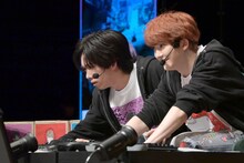 真剣な表情でコースを読むリョウガ（奥 / 超特急）と、リョウガのプレイを見守るユーキ（手前 / 超特急）。