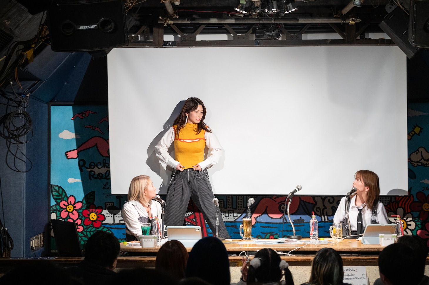 スクリーンの裏で生着替えをしてデビュー当時の衣装を披露する柴田あゆみ（中央）。